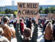 woman holds up sign at a rally saying "we need a change"