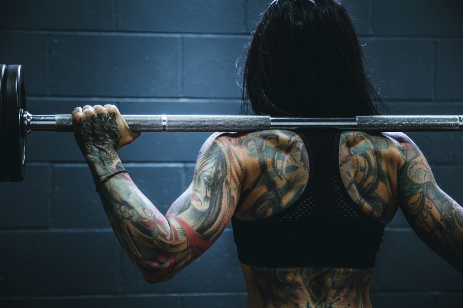 Woman with lots of tattoos lifting weights